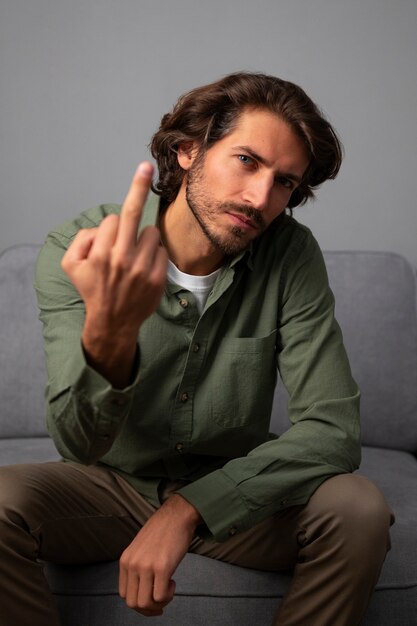 Man showing middle finger while sitting on the sofa