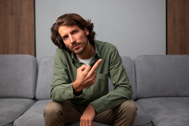 Man showing middle finger while sitting on the sofa