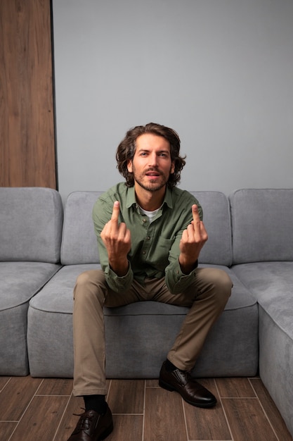 Man showing middle finger while sitting on the sofa