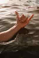 Free photo man showing shaka hand sign in water