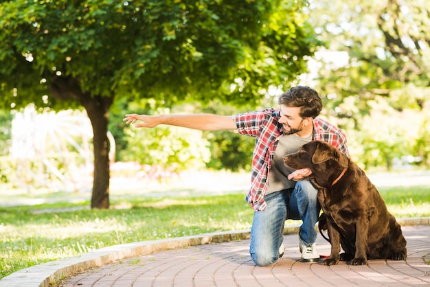 Foto gratuita uomo che mostra qualcosa al suo cane nel parco