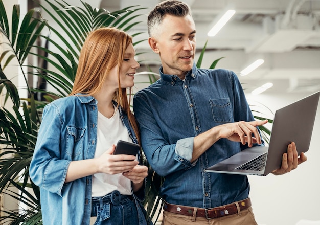 Free photo man showing something on a laptop to his coworker