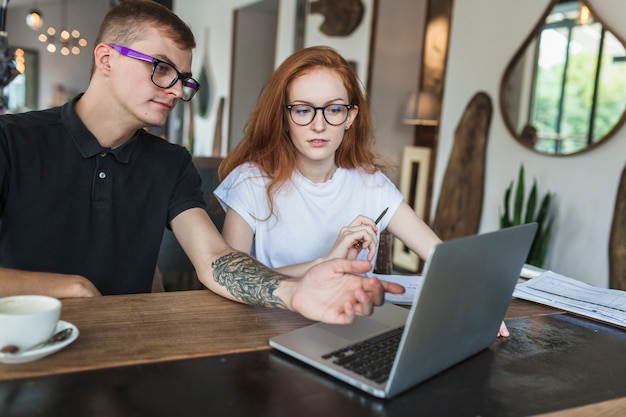 Man showing something to woman at laptop screen