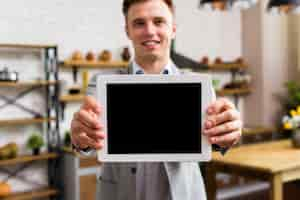 Free photo man showing tablet to camera mockup