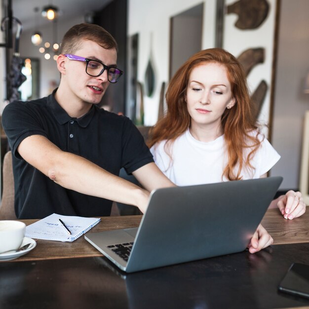 Man showing woman laptop screen