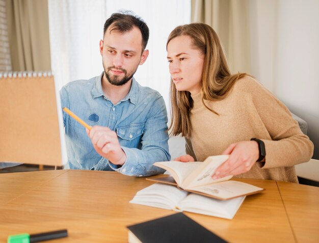 Man showing woman something he wrote on notebook