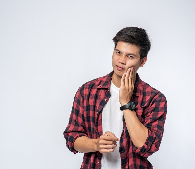 A man sick with a toothache and a hand holding on the cheek