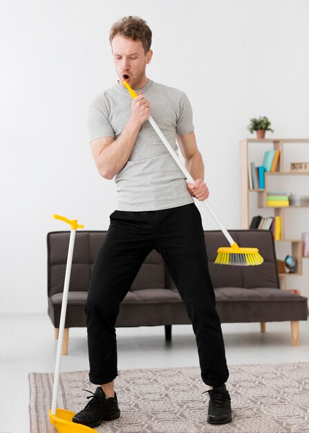 Free photo man singing at broom while cleaning