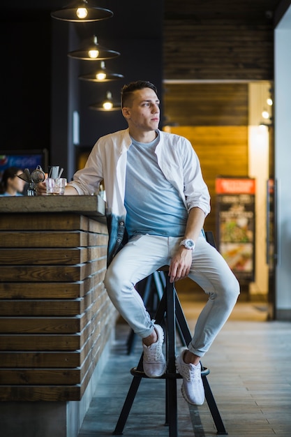 Free photo man sitting at bar counter looking away