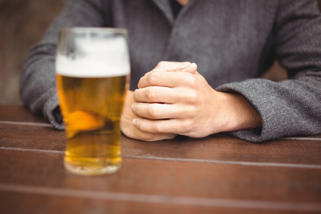 テーブルの上のビールのグラスとバーに座っている男