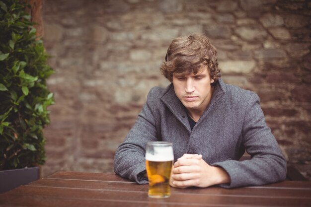 テーブルの上のビールのグラスとバーに座っている男