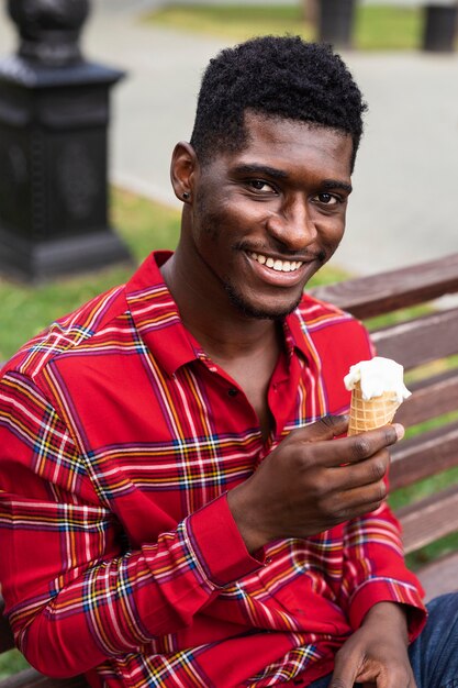 ベンチに座って、アイスクリームを食べる男