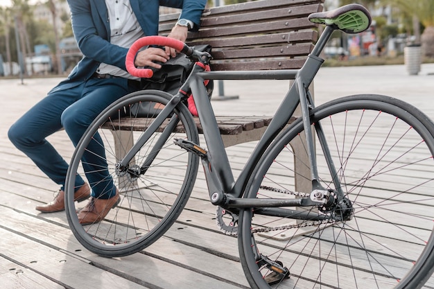 屋外で自転車の横のベンチに座っている男