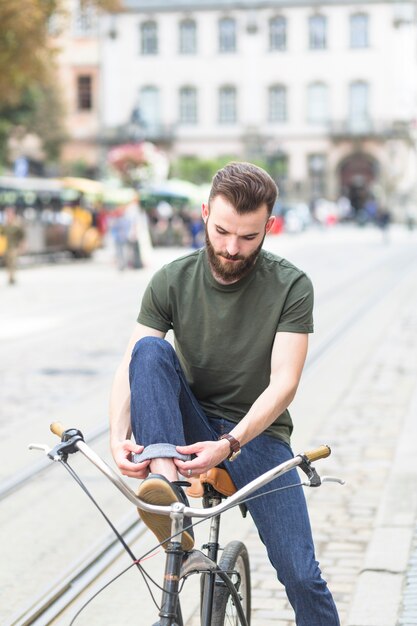 Man sitting on bicycle folding his jeans