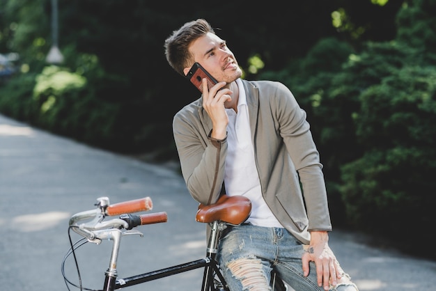 Человек, сидя на велосипеде, говорить по мобильному телефону