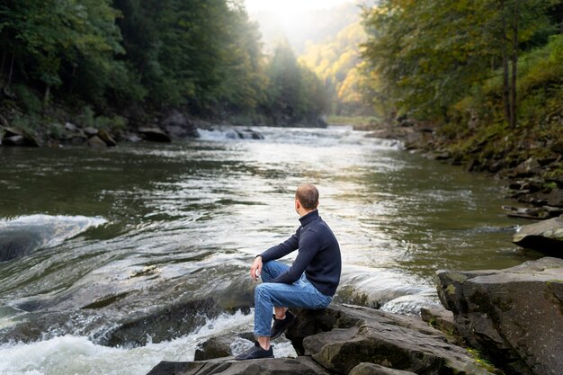 man sitting by the river side view