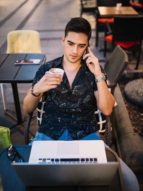 Человек, сидя в кафе, говорить на мобильном телефоне