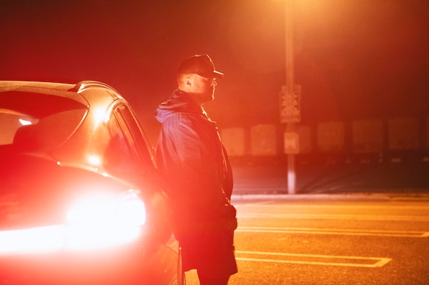 Man sitting next to car at night