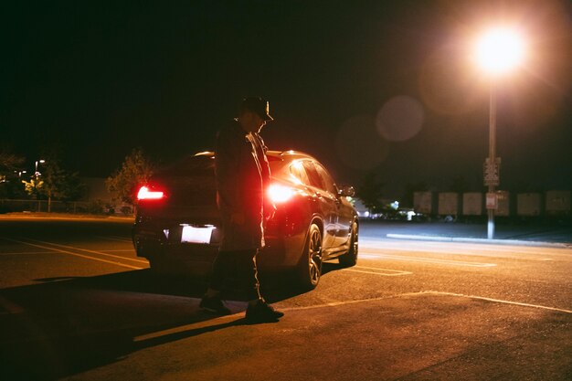 Man sitting next to car at night