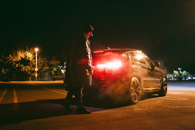 Man sitting next to car at night