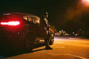 Free photo man sitting next to car at night