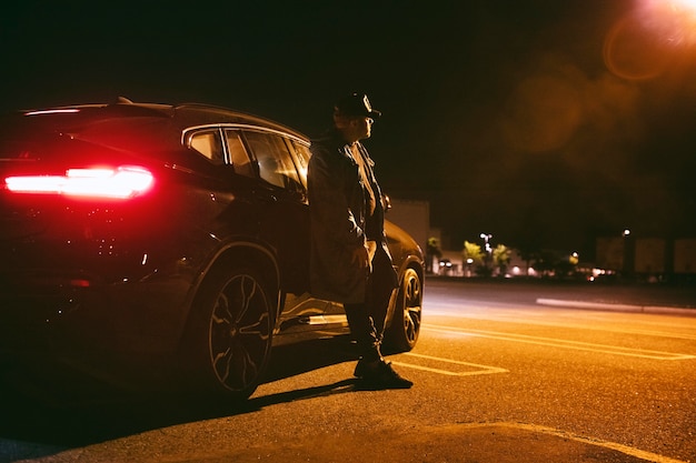 Man sitting next to car at night