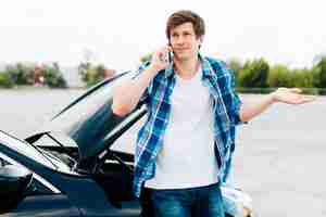 Free photo man sitting on car and talking on phone