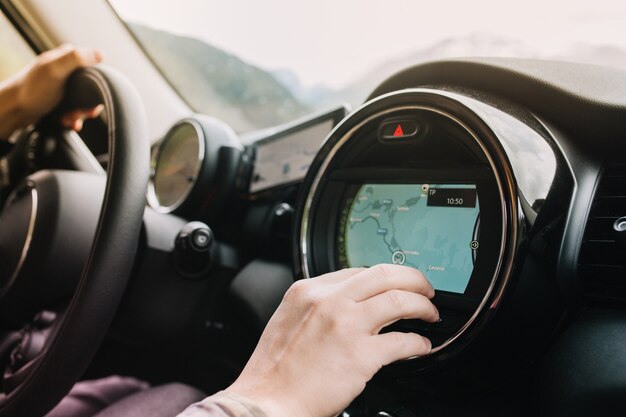 Man sitting in the car with black interior and looking at the new route laid by the navigator