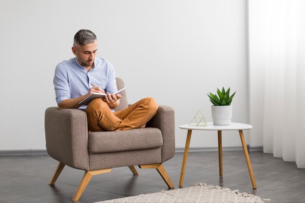 Man sitting on chair and writing on his agenda