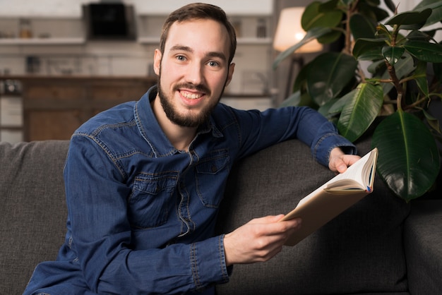 Man sitting on couch and holding book
