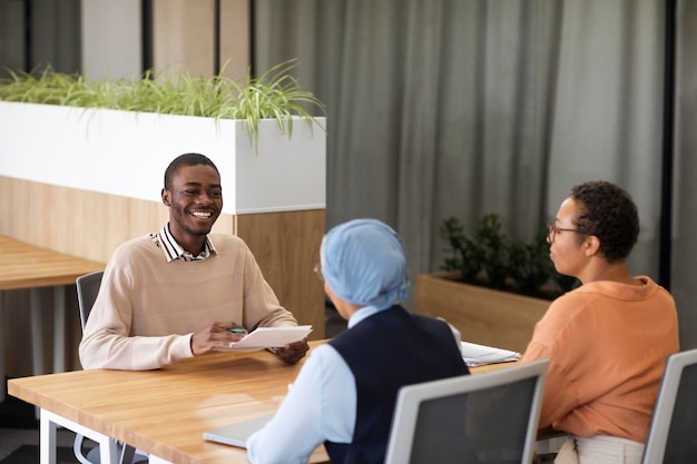 Free photo man sitting down for an office job interview at desk with his employers