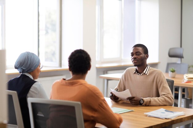 Man sitting down for an office job interview at desk with his employers