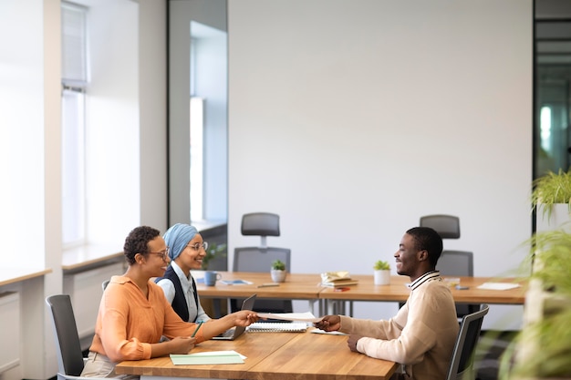 Free photo man sitting down for an office job interview at desk with his employers