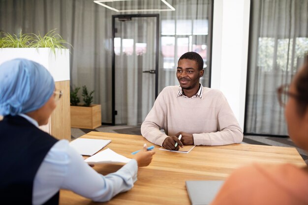 Man sitting down for an office job interview at desk with his employers