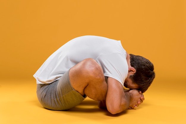 Uomo che si siede nella posa di yoga della curvatura di andata