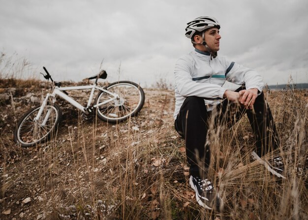 Man sitting on the grass next to his mountain bike