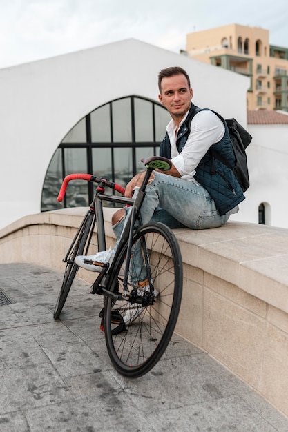 Foto gratuita uomo seduto accanto alla sua bici