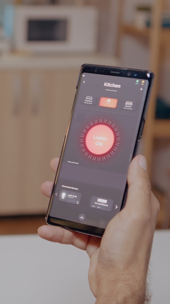 スマートフォンを保持している自動化ライトシステムで家に座っている男