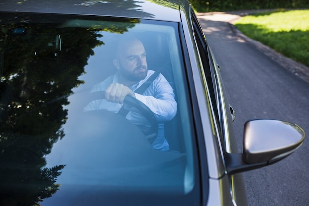 Человек, сидящий внутри автомобиля, видимый через ветровое стекло