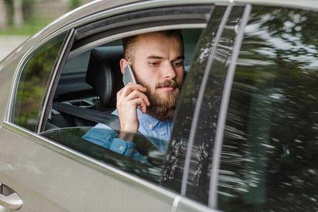 Человек сидит в машине с помощью мобильного телефона