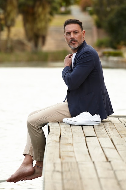 Free photo man sitting on a jetty posing