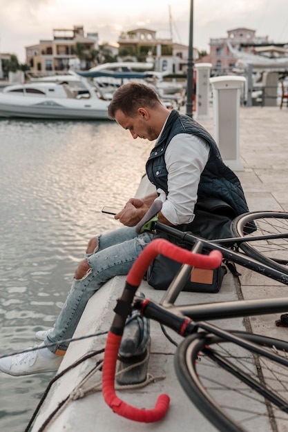 Foto gratuita uomo seduto accanto a un lago con la sua bici