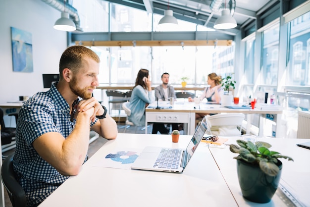 Free photo man sitting at laptop in office