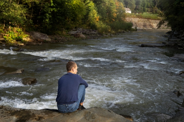 Free photo man sitting in nature full shot