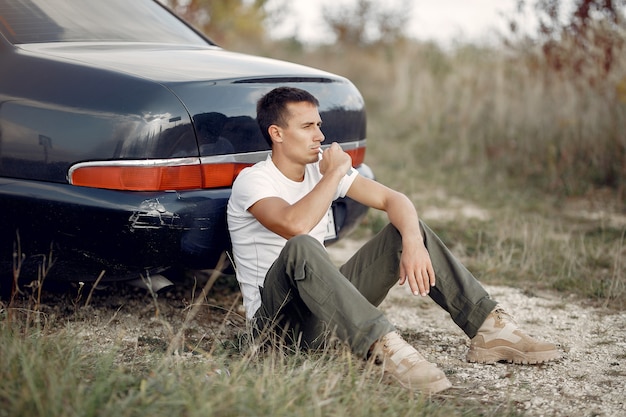 Free photo man sitting near the  broken car