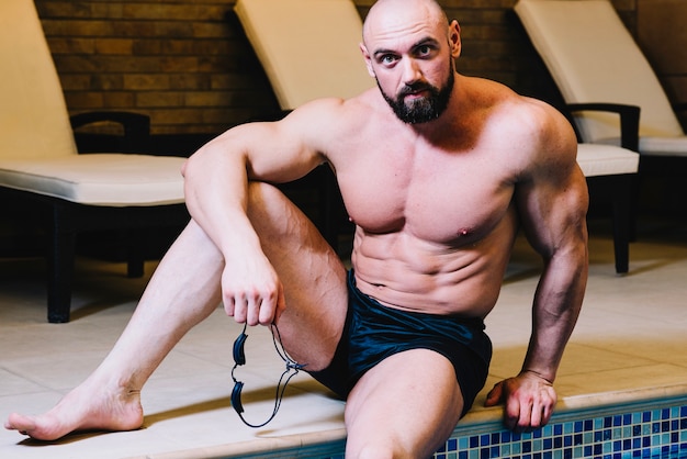 Free photo man sitting near swimming pool