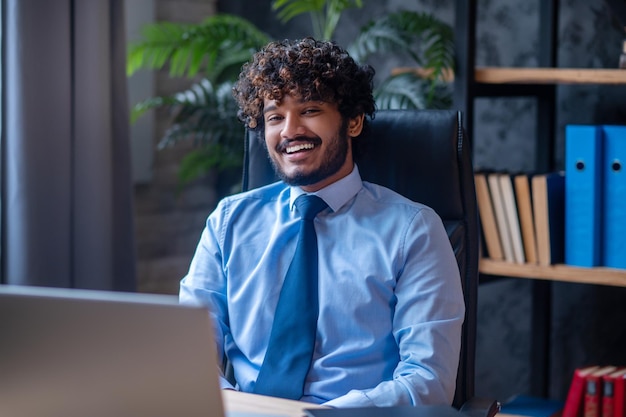 Free photo man sitting at office table looking at camera