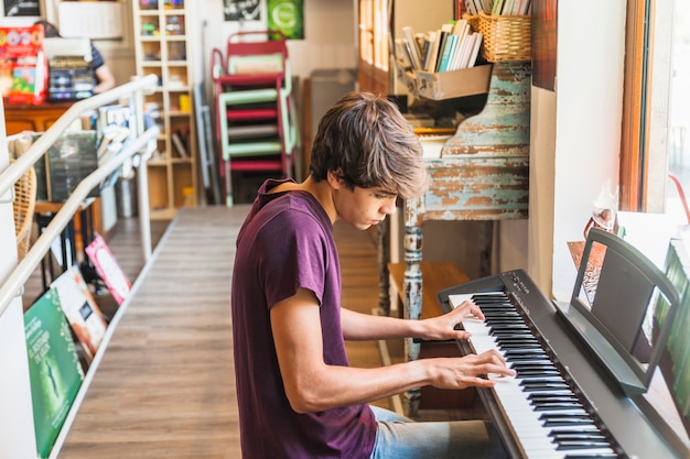 Free photo man sitting and playing synthesizer