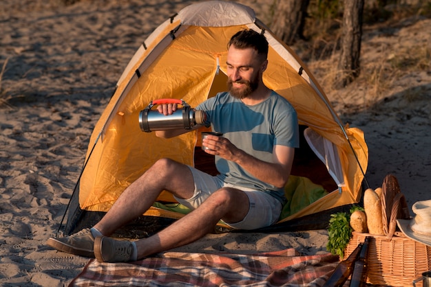 Foto gratuita uomo seduto e versando dal thermos