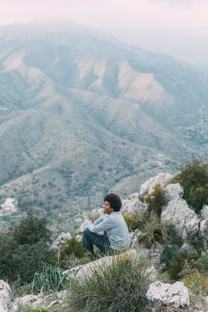 Free photo man sitting on rock in nature